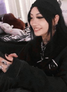 a woman wearing a black beanie and a black sweater is smiling