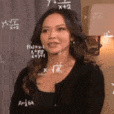 a woman is standing in front of a chalkboard with mathematical equations on it
