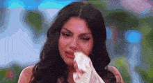 a woman is crying while holding a piece of paper in her hand .