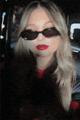 a blonde woman wearing sunglasses and red lipstick