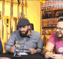 two men are sitting at a table with a figurine of a knight with the number 89 on his skirt