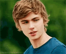 a young man with blonde hair is wearing a blue shirt with chandlerfknriggs on the bottom