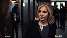 a woman is standing in a hallway with nbc written on the bottom right