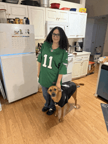 a woman wearing a green jersey with the number 11 standing next to a dog
