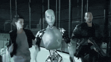 a man holding a gun stands next to a robot and a woman