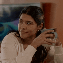 a woman in a white shirt is holding a blue mug