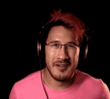 a man wearing headphones and a pink shirt is making a funny face .