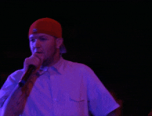 a man wearing a red hat and a white shirt is holding a microphone