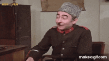 a man in a military uniform with a mustache is sitting in a chair eating something .