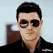 a close up of a man wearing sunglasses and a black suit