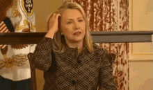 a woman in a black and white polka dot shirt is scratching her head