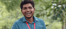 a man with a lanyard around his neck is smiling at the camera and the time is 6:56 pm
