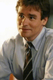 a man wearing a blue shirt and tie is looking at the camera