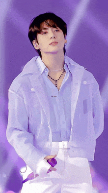 a man wearing a purple jacket and white pants holds a purple microphone
