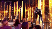 a group of people are standing on a stage watching a group of people perform on stage .