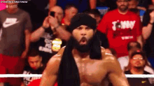 a man with a beard is standing in a boxing ring with a crowd behind him and a shirt that says tommy