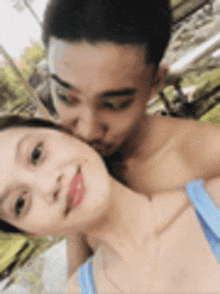 a man is kissing a woman on the neck while they are posing for a picture .