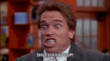 a man in a suit and tie is making a funny face and saying shut uuuuuuup .