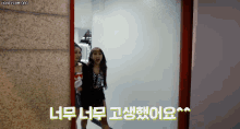 two women are standing next to each other in a room with korean writing on the door .