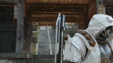 a person holding a sword in front of a wooden gate