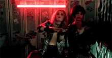 a couple of women are standing next to each other in a dark room with red lights .