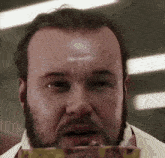 a man with a beard is wearing a white shirt and eating a piece of meat