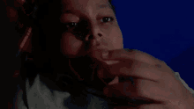 a young boy is laying in a dark room looking at the camera