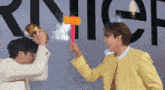 a man in a yellow jacket is holding a toy hammer in front of a sign that says choco latez