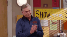 a man clapping in front of a sign that says " show your "