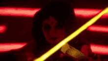 a woman is holding a yellow light saber in her hand in a dark room .
