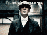 a man in a suit and hat is standing in front of a sign that says " грамотей запел в чат "