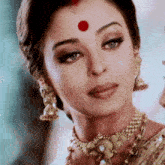 a woman with a red dot on her forehead is wearing a necklace and earrings