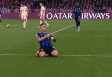 a soccer player is kneeling on the field in front of a qatar airways banner