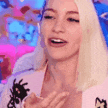 a woman with blonde hair is clapping her hands in a pixelated image .