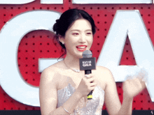 a woman holding a microphone in front of a bazaar gala sign
