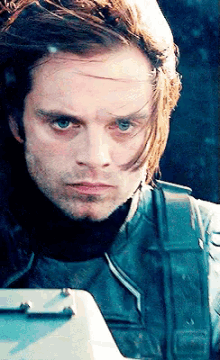 a close up of a man 's face with long hair and blue eyes