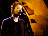 a man singing into a microphone with the fox logo behind him