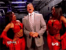 a man in a suit and tie is standing next to two women in red outfits with u-d written on the bottom