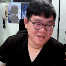 a man wearing glasses and a black shirt is sitting in a chair