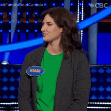 a woman wearing a green shirt and a gray jacket with a name tag that says megan