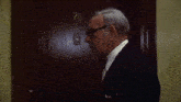 a man in a suit is standing in front of a door with the number 70 on it