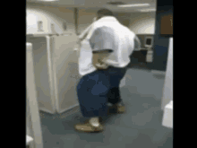a man in a white shirt and blue pants is dancing in a hallway
