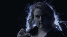 a woman wearing glasses and a black jacket is standing in the dark .