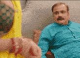 a man with a mustache is sitting on a couch