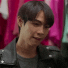 a close up of a young man wearing a leather jacket and a gray shirt .