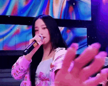 a woman is singing into a microphone while wearing a purple jacket