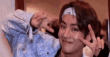 a man wearing a headband is making a peace sign with his hands .