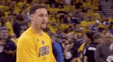 a basketball player is standing in front of a crowd wearing a yellow shirt that says `` strength in numbers '' .
