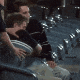 a man in a black and white striped shirt is sitting next to another man in a blue chair