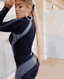 a woman wearing a black jumpsuit and hoop earrings